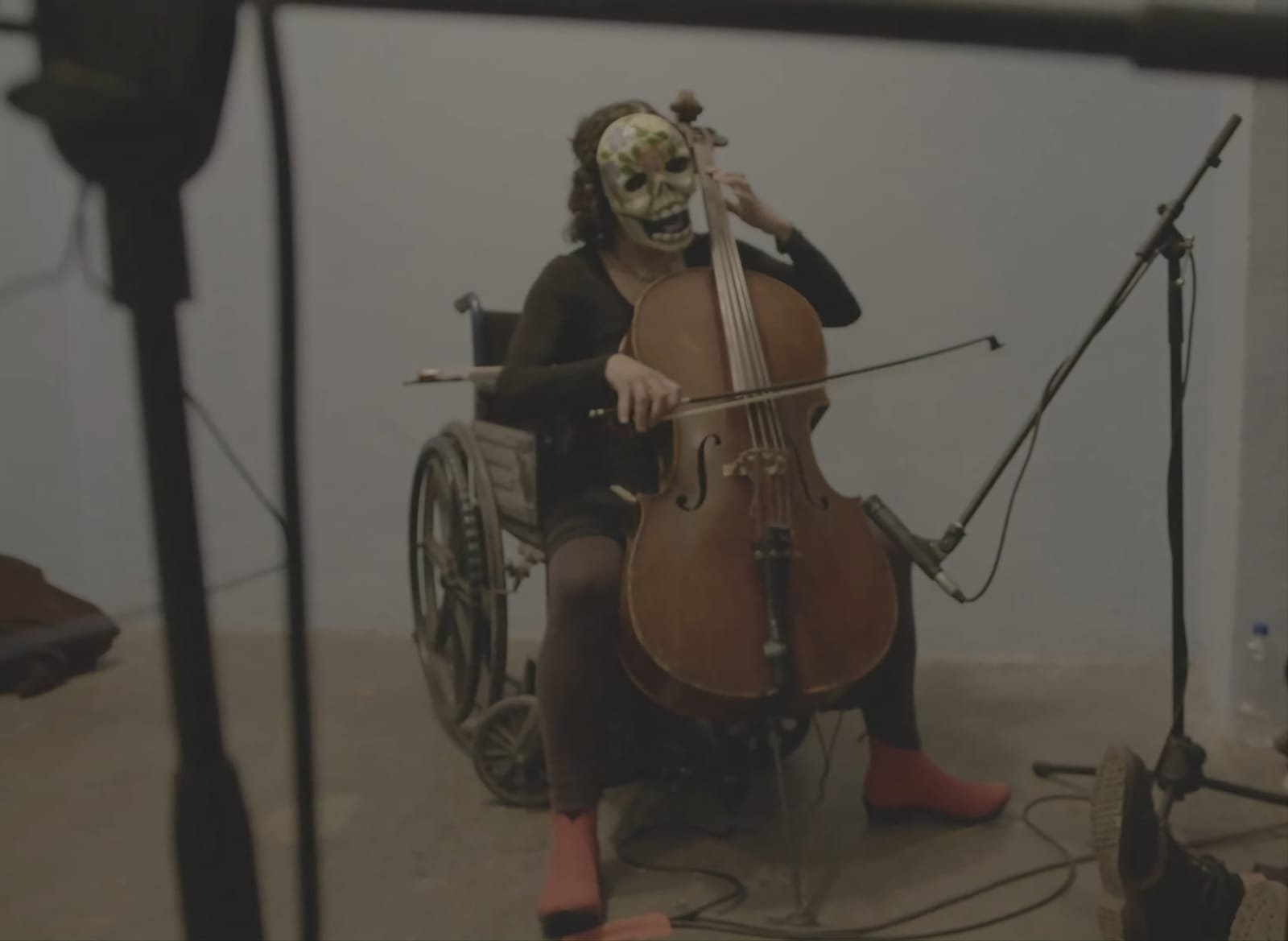 Fotografía de Maricarmen Graue, tocando el cello sobre una silla de ruedas y con una máscara de calavera